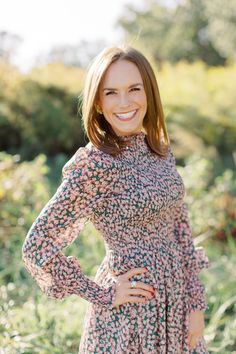 a woman in a floral dress posing for the camera with her hands on her hips