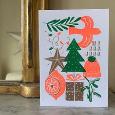 a christmas card with an orange bird and tree surrounded by presents on a marble surface