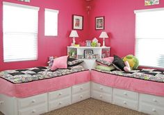 two twin beds in a room with pink walls and white drawers on the bottom floor