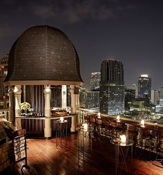 an outdoor bar with candles lit up in front of the city skyline