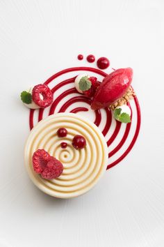 a white plate topped with a cupcake covered in icing and raspberries