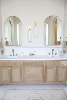 a bathroom with two sinks, mirrors and rug on the floor in front of it