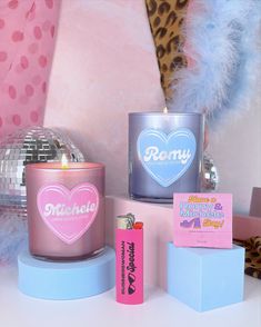 two candles are sitting next to each other on a table with pink and blue decorations