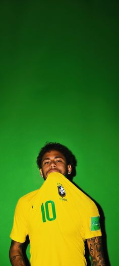 a man in a yellow soccer jersey poses for a photo with his hands on his hips