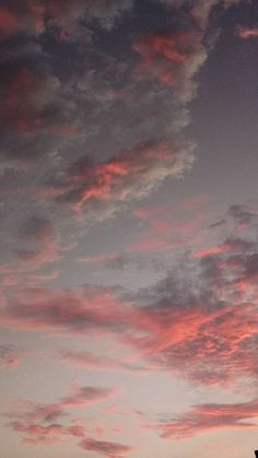 an airplane is flying in the sky at sunset with clouds and pinkish hues