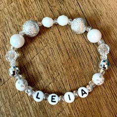 a white beaded bracelet with the word aleia written on it and some beads