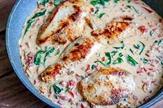 some chicken is cooking in a pan on the table with gravy and spinach