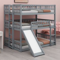 a bunk bed with a slide next to it in a pink walled room that is also used as a desk