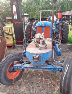 an old blue tractor sitting in the dirt