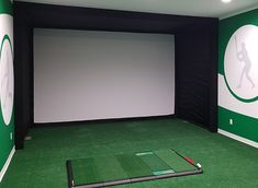 an indoor golf simulator with green carpet and white walls