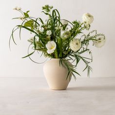 a white vase filled with flowers on top of a table