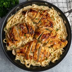 a pan filled with chicken and pasta next to parmesan cheese on a table