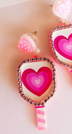 pink and white lollipop earrings with hearts on them