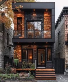 a black and brown house with stairs leading up to the front door, surrounded by brick buildings