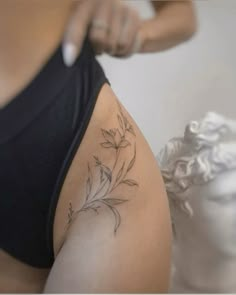 a woman is getting her tattoo done on her thigh with flowers in the back and behind her