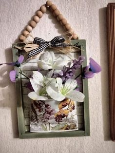 a wooden frame with flowers in it and a beaded necklace hanging on the wall