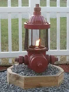 a red fire hydrant sitting on top of gravel next to a white picket fence