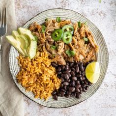 a plate with rice, beans, avocado, and chicken next to a fork