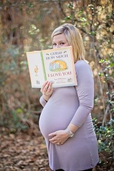 a pregnant woman holding up a book in front of her face