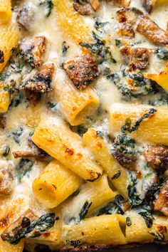 a casserole dish with pasta, sausage and spinach on it's side