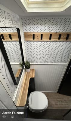 the interior of a small bathroom with a toilet and mirror on the wall next to it