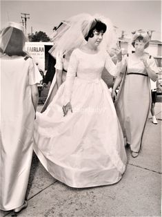 black and white photograph of two brides walking down the street with their veil blowing in the wind