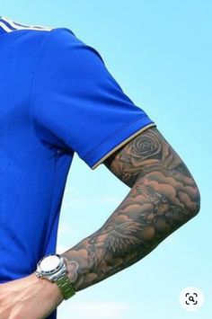 a man with tattoos on his arm wearing a blue shirt