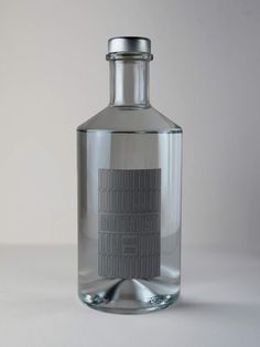 a glass bottle that is sitting on a table in front of a white wall and grey background