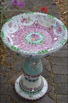 a mosaic glass pedestal with flowers in the background