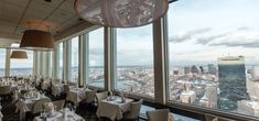 a restaurant with large windows and tables set up for dinner in front of the cityscape