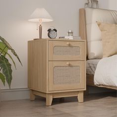 a night stand with two drawers and a clock on top, next to a bed