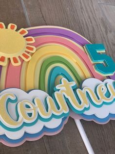 a cake topper with the number five on it and a rainbow in the background