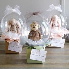 three stuffed animals in clear glass balls with tags