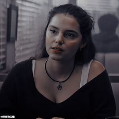 a woman sitting at a table in front of a window with her hands on her chest