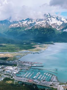 an aerial view of a marina and mountains in the distance with snow - capped peaks