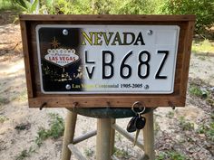 a license plate for nevada is displayed on a wooden stand in the dirt near trees