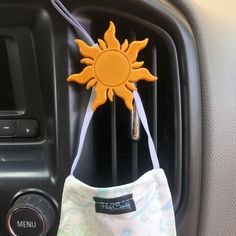 an air freshener hanging from the side of a car's dash board with a sun decoration on it