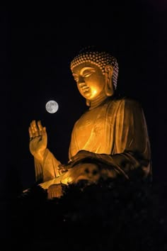 a large buddha statue sitting in the dark with a full moon behind it's head