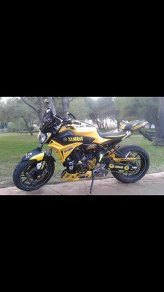 a yellow and black motorcycle parked in front of a tree