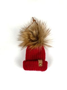 a red knitted hat with a fur pom