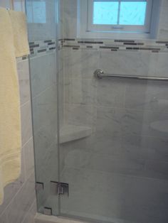 a glass shower door in a white bathroom