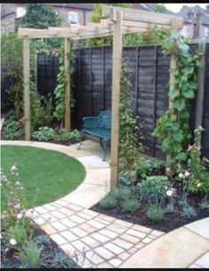 an outdoor garden with green plants and wooden trelliss on the fenced in area