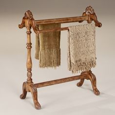 an old wooden towel rack with two towels hanging from it's sides and one on the other side