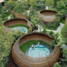 an aerial view of a swimming pool surrounded by trees and bushes with people in it