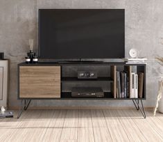 an entertainment center with a television and bookshelf in front of a concrete wall