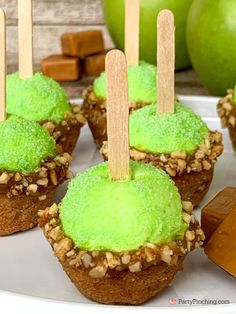 there are some green cupcakes with wooden sticks sticking out of them on a plate