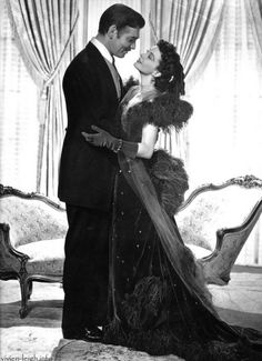 an old black and white photo of a man and woman in formal dress standing next to each other