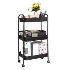 a black rolling cart with books, magazines and flowers on it's top shelf