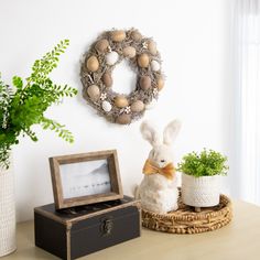 a white rabbit sitting on top of a table next to a box and potted plant