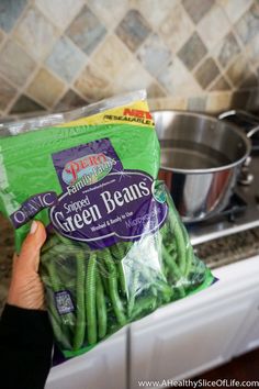 someone is holding up some green beans in the kitchen